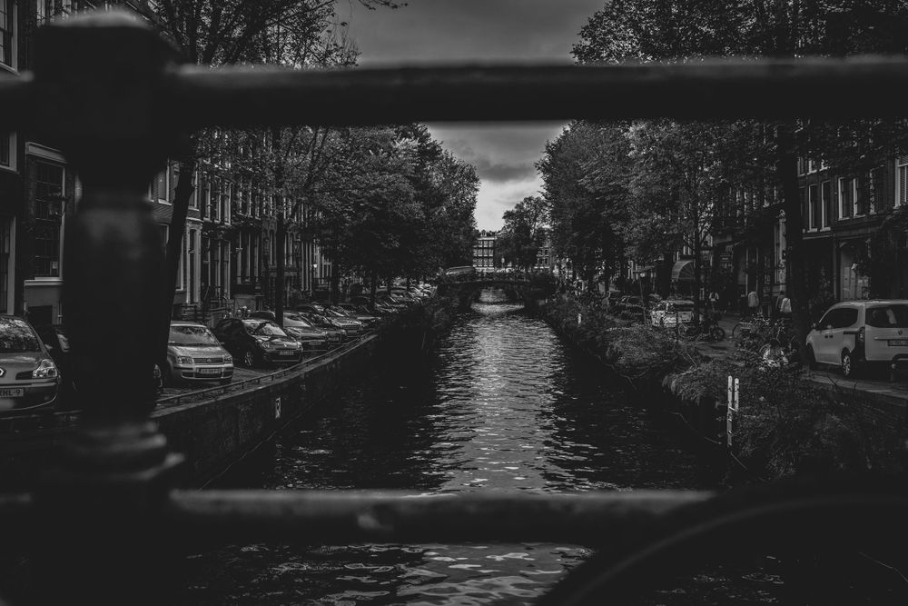 Svartvit bild av en kanal i Amsterdam med bro och cyklar