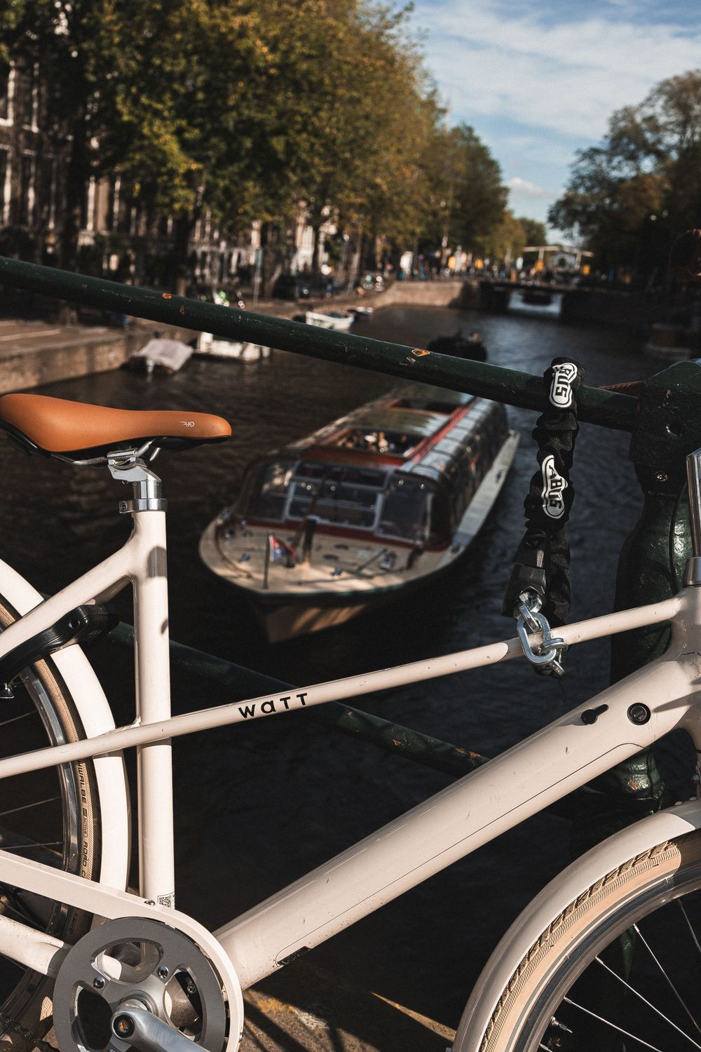 Cyklar vid en kanal i Amsterdam med båt i bakgrunden