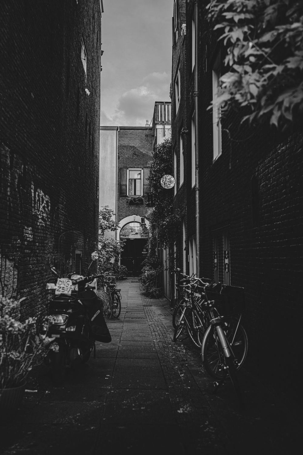 Svartvit bild av en smal gata i Amsterdam med cyklar