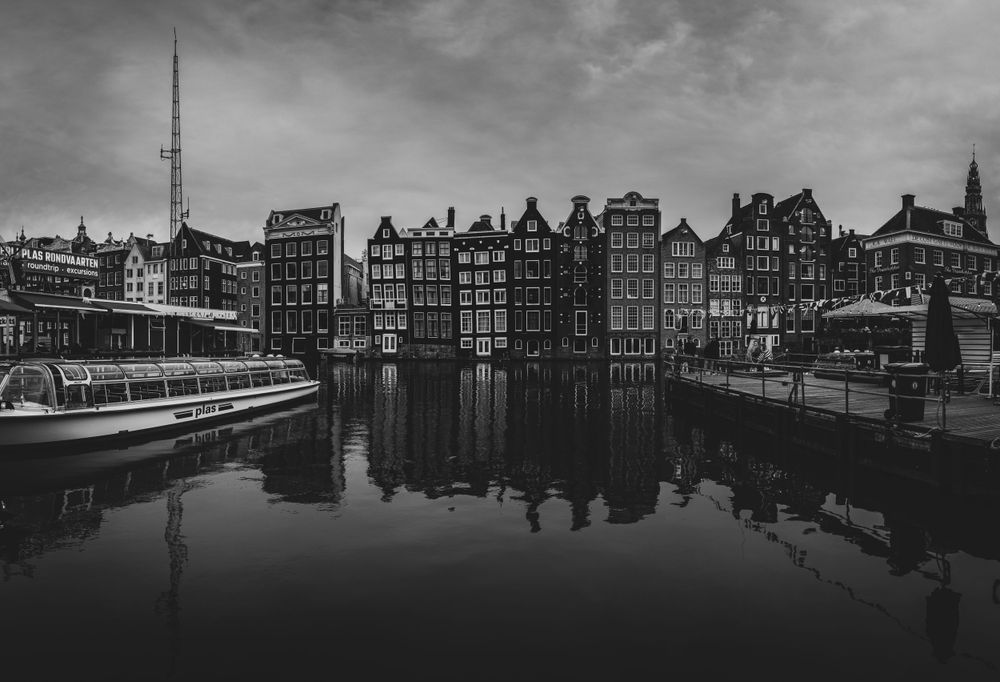 Svartvit panoramabild av en kanal i Amsterdam med byggnader