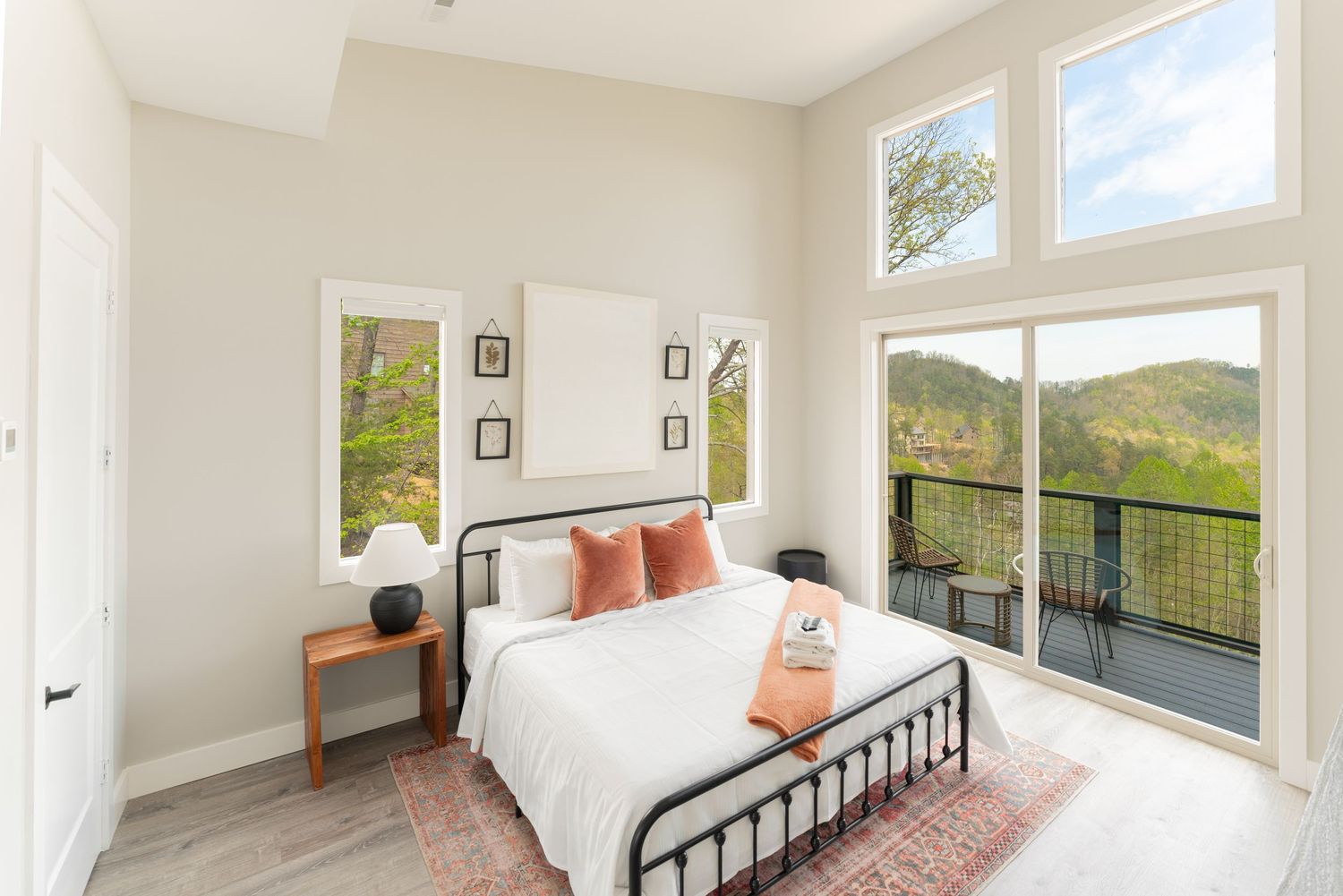 Bright bedroom with panoramic mountain views, metal bed frame, and sliding glass doors to balcony.