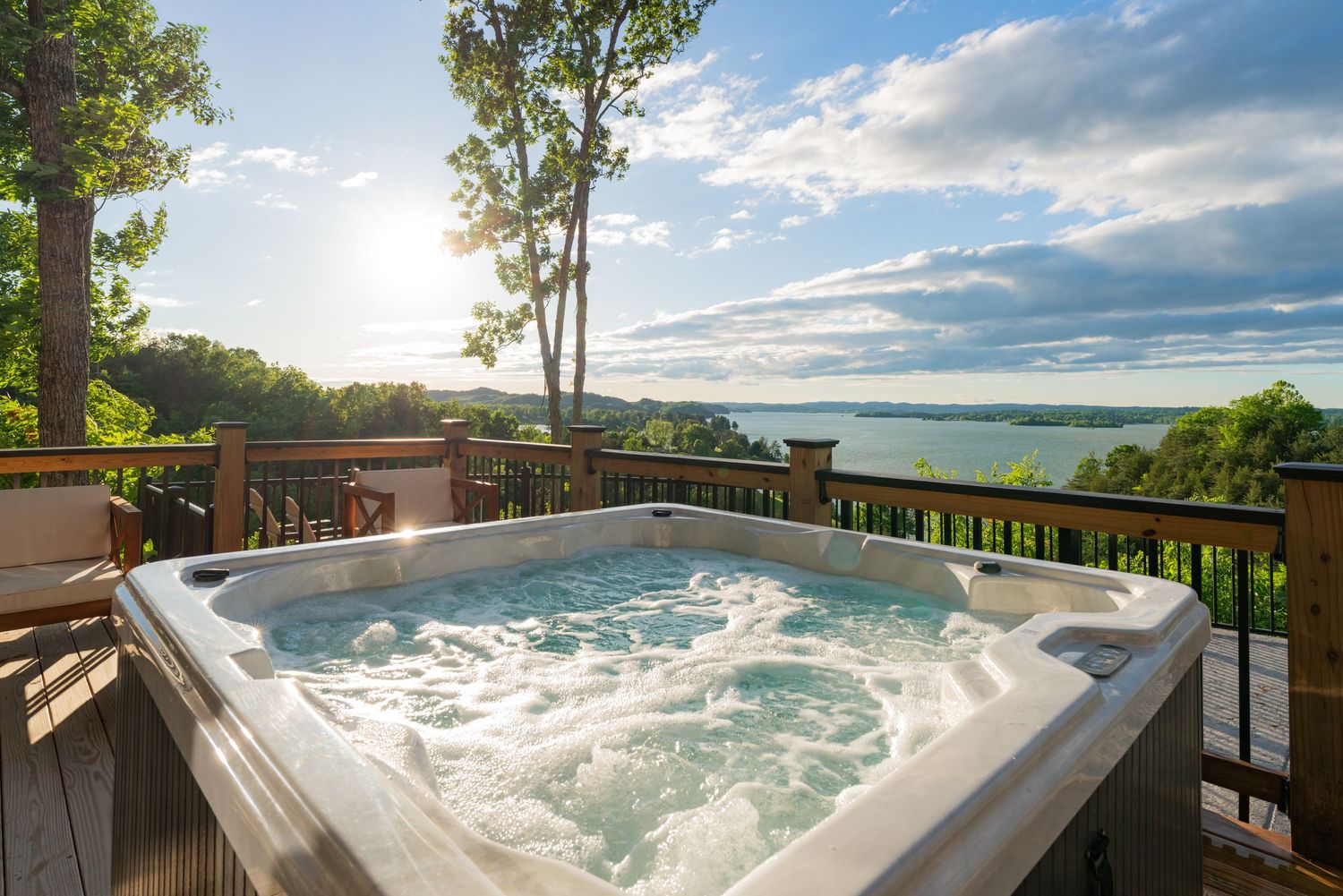 Luxurious hot tub on wooden deck overlooking a serene lake and tree-lined shore.