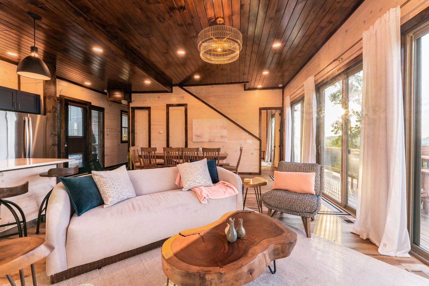 Cozy living room with wooden ceiling, white sectional sofa, and large windows overlooking mountain views.