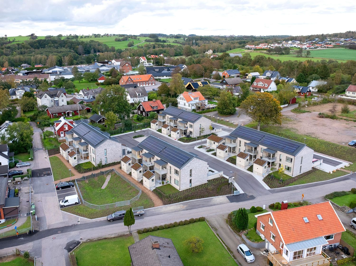 Aerial panoramic view of modern residential neighborhood with white houses and green lawns in suburban area.