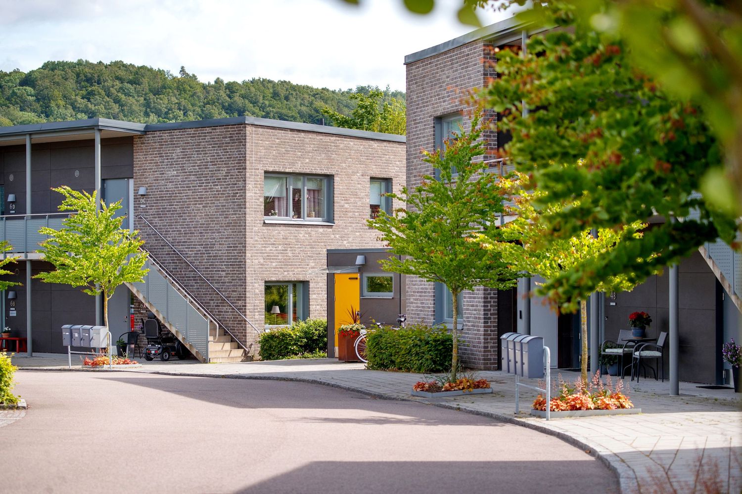 Modern brick office buildings with large windows and landscaping line a curved driveway on a sunny day.