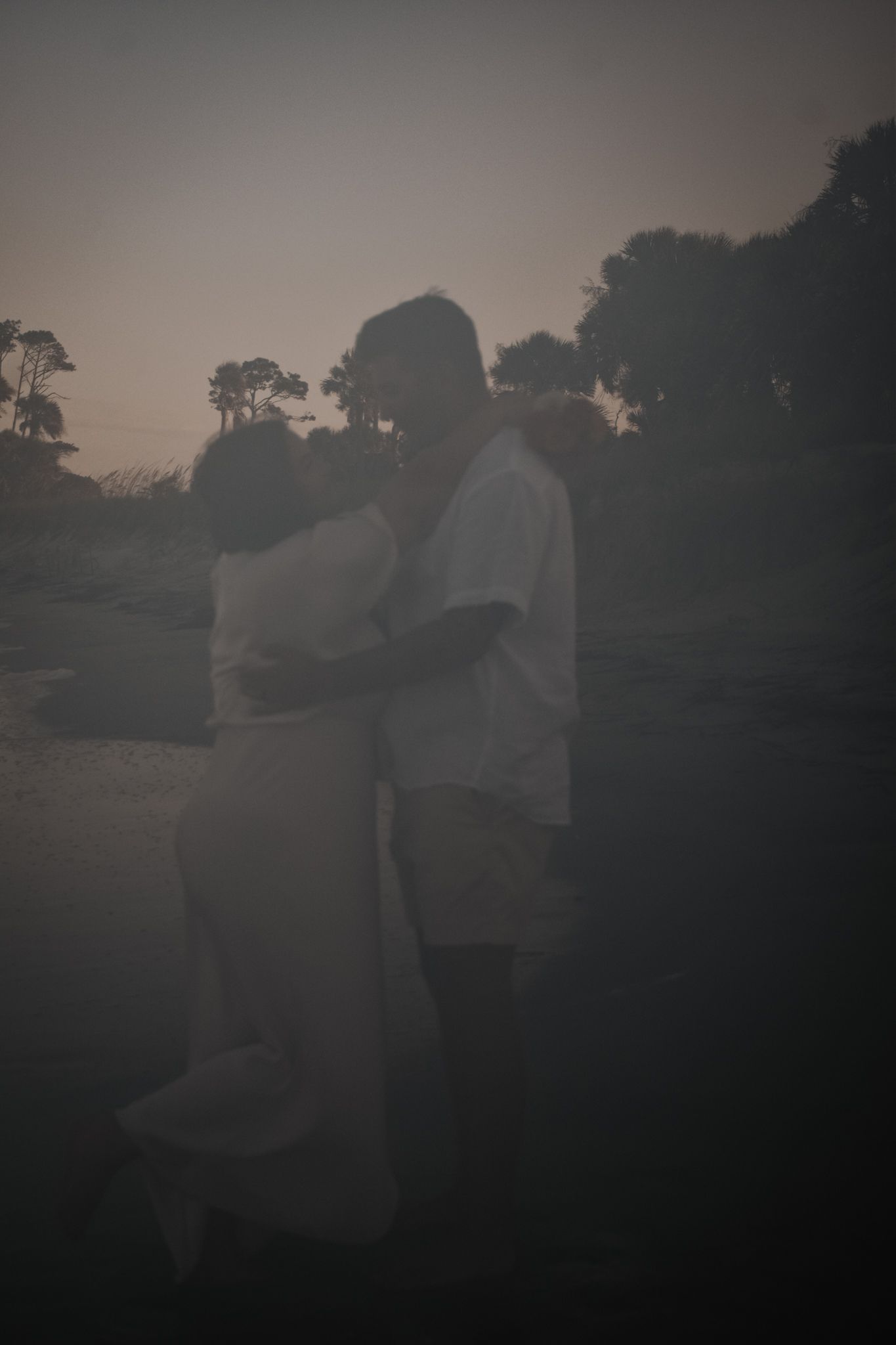 A moody silhouette portrait of a couple embracing at sunset.