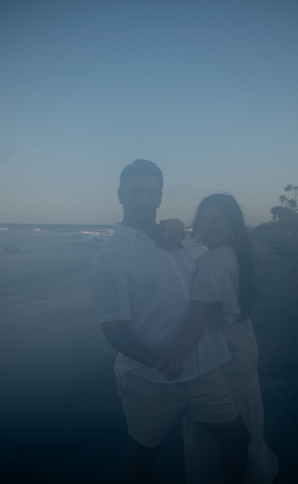 A couple enjoying a quiet moment overlooking the ocean at twilight.