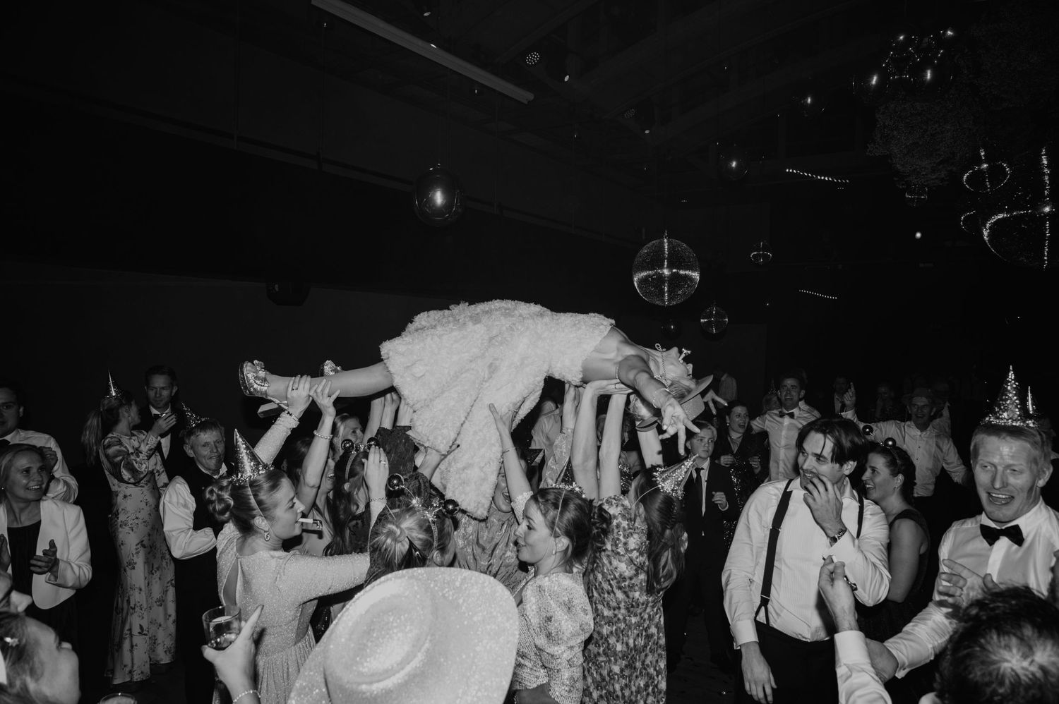 A lively wedding reception dance floor scene captured in black and white photography.