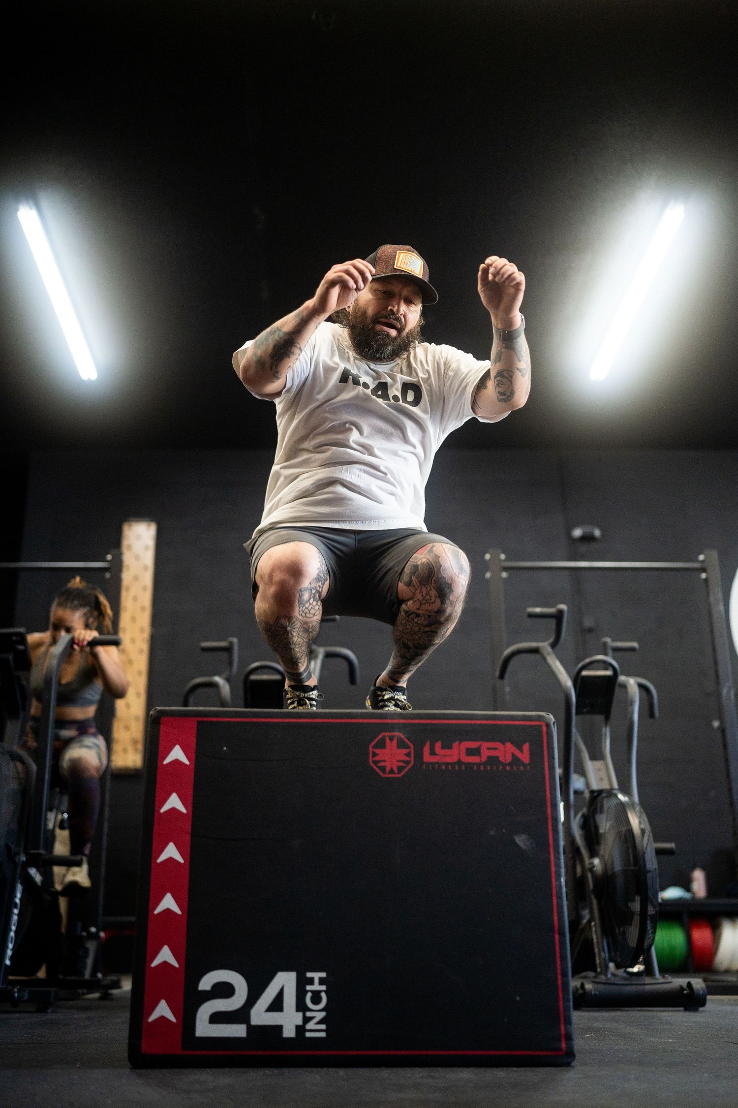 Athlete performs box jump on 24-inch WORN box in dimly lit gym.