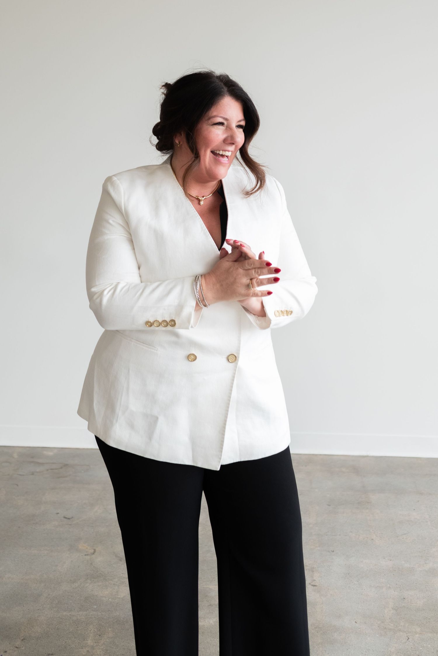 Professional studio portrait showing joyful expression and crisp white double-breasted blazer.