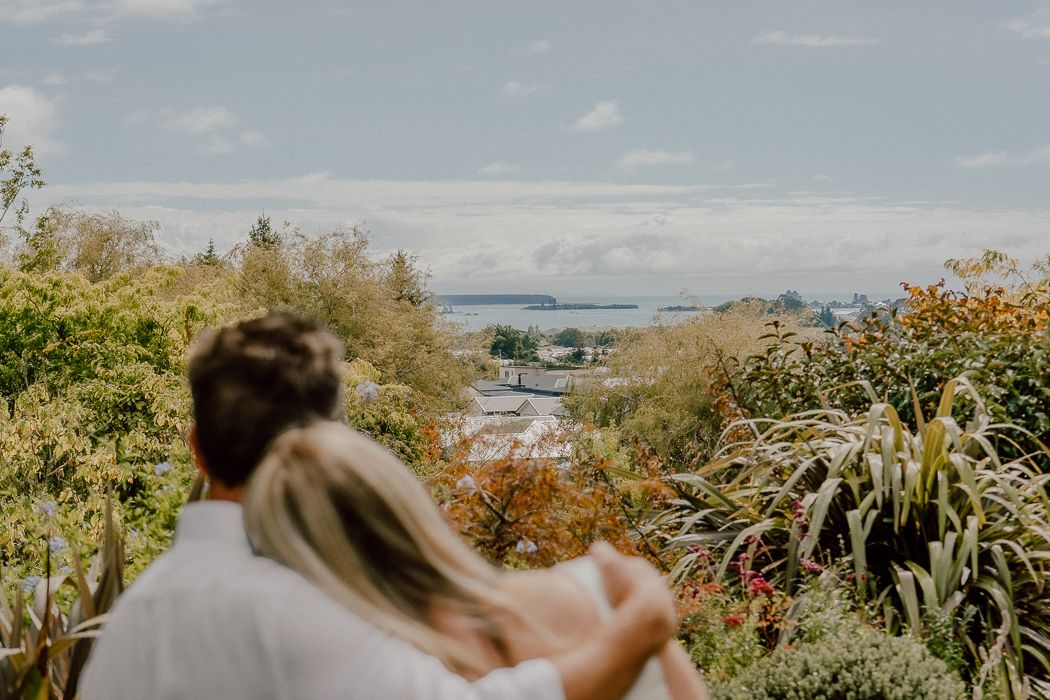 A couple shares a tender moment together by the waterfront on an overcast day.