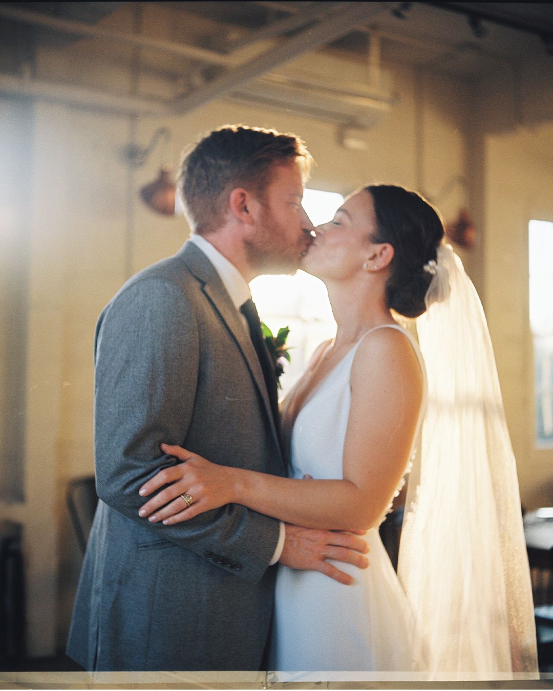 Intimate wedding moment captured in soft window light.