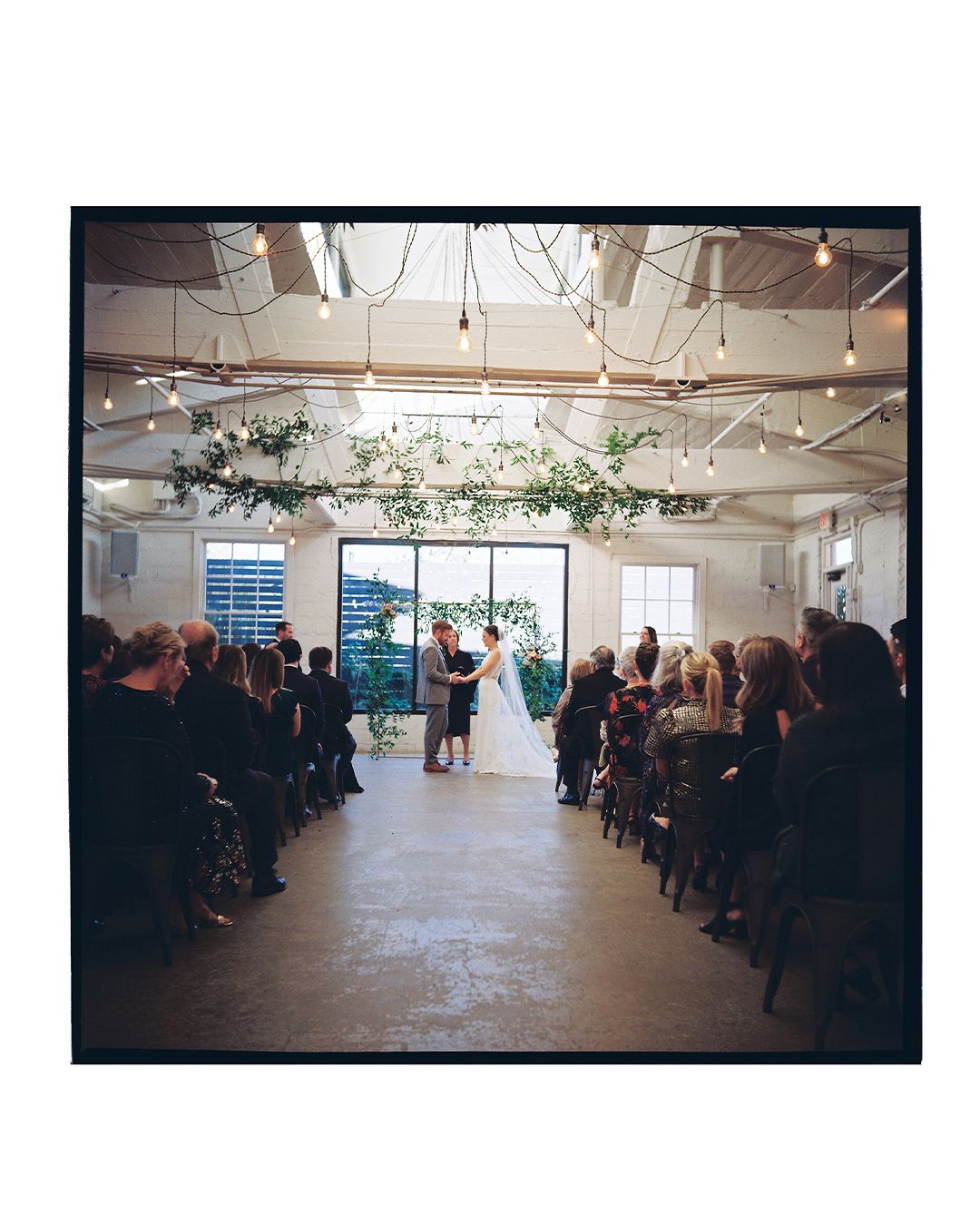 Wide angle view of a wedding ceremony venue with guests seated in an industrial-style space.
