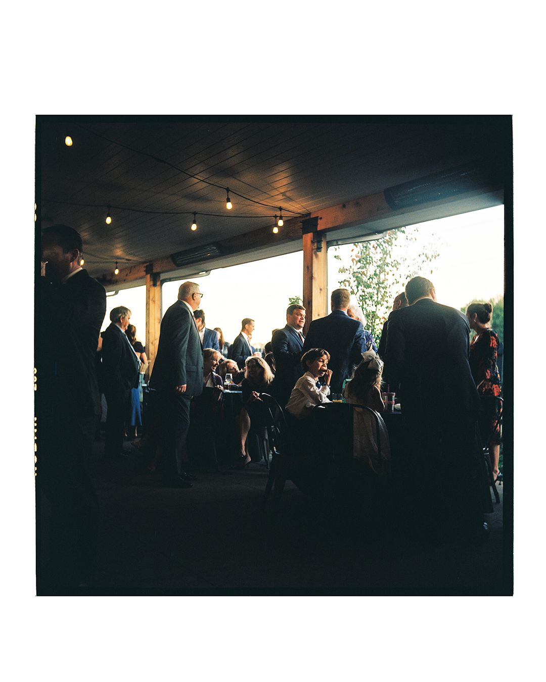 Silhouetted wedding reception guests mingling in a dimly lit venue space.