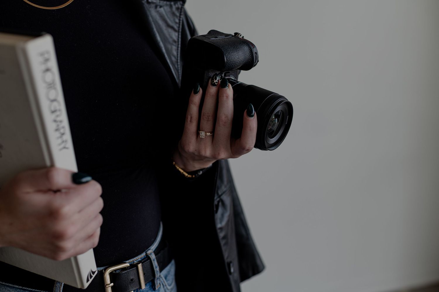 Close up of hands holding professional camera equipment against dark background.