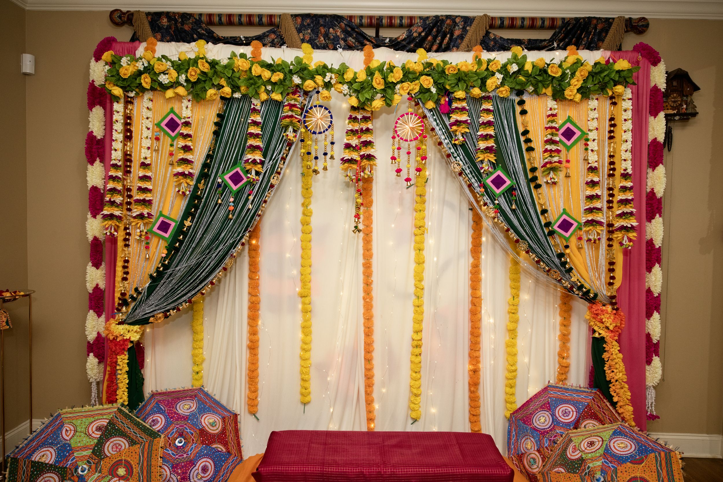 Colorful Indian wedding mandap decorated with marigold garlands, teal drapes, and traditional floral arrangements.