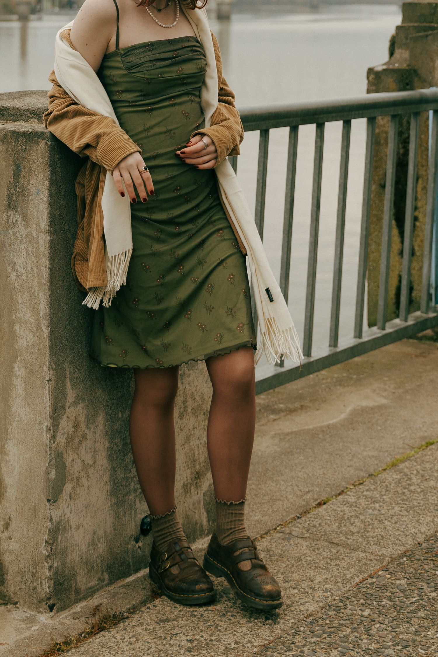 Green dress and tan cardigan outfit styled with combat boots on a concrete walkway.