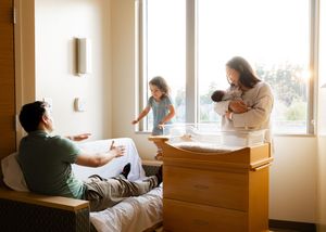 A family shares a tender moment together in a bright sunlit room with large windows.