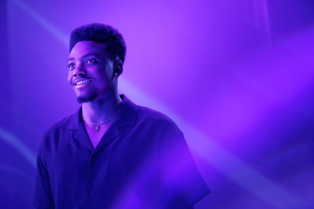 Portrait against purple backdrop showing dramatic side lighting effects.