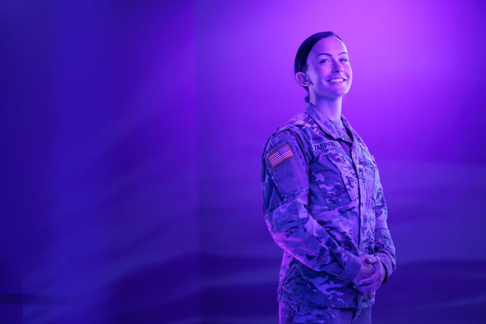 Military service member poses confidently under purple studio lighting.