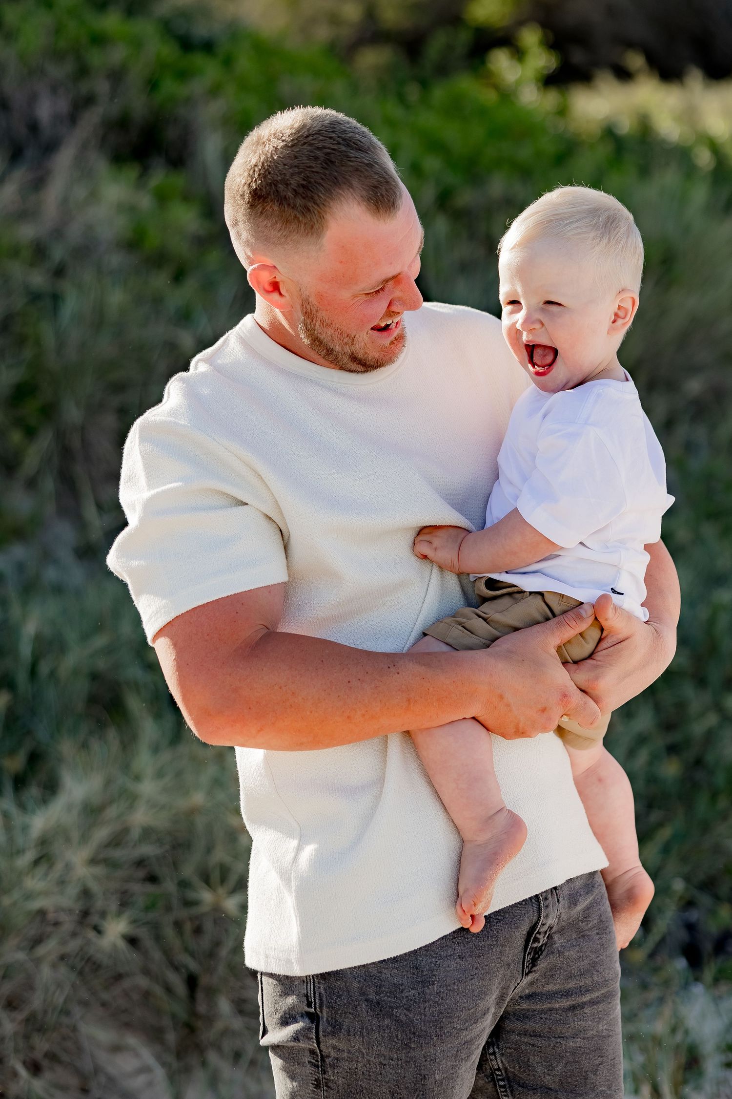 Parent and toddler sharing joyful moment together outdoors.
