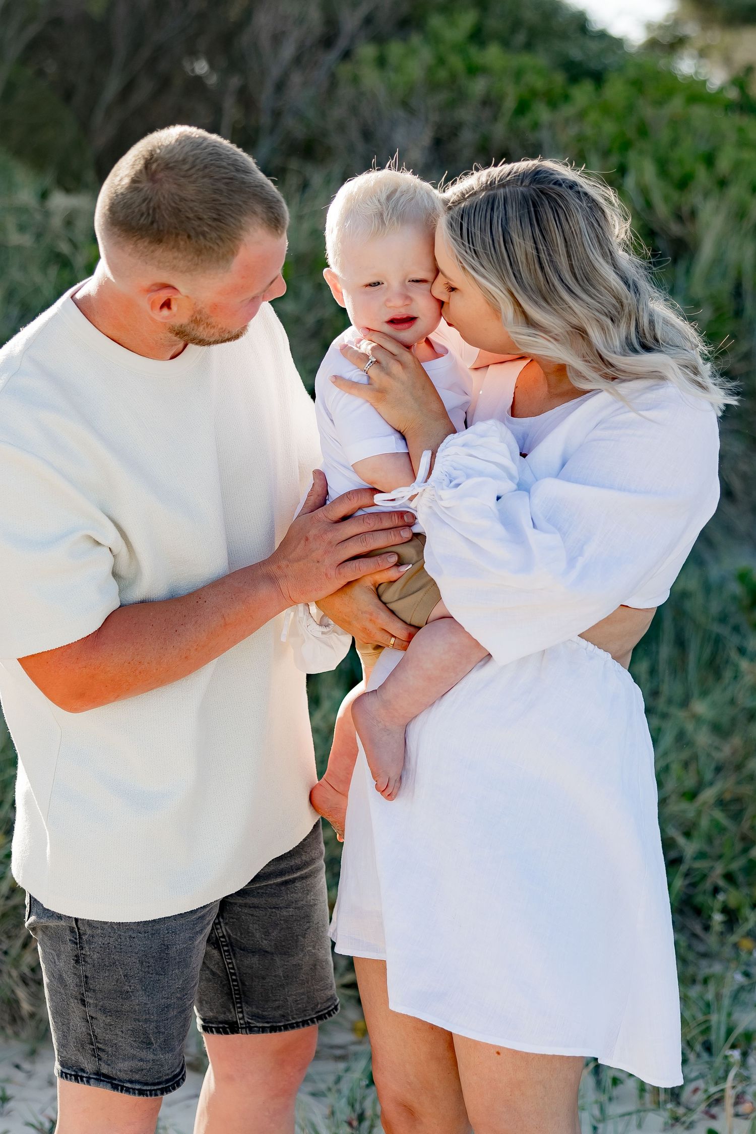 Family sharing intimate moment and laughter on sandy dunes.