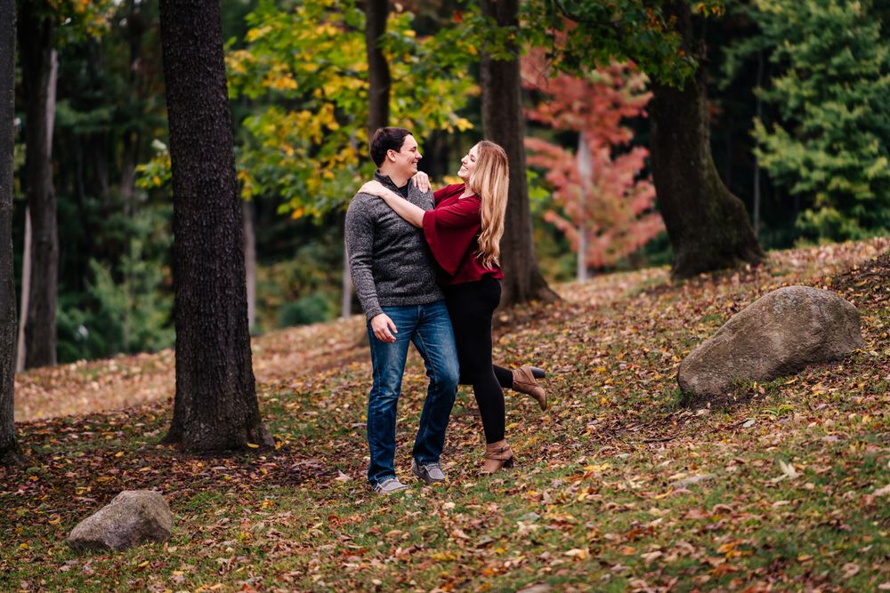 A romantic autumn scene with a couple embracing among fallen leaves and trees.