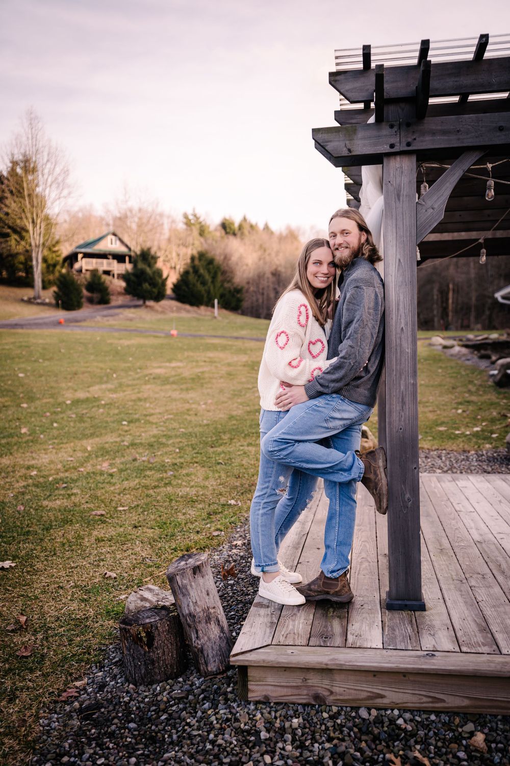 A couple sharing an intimate moment on a rustic wooden deck overlooking a field.