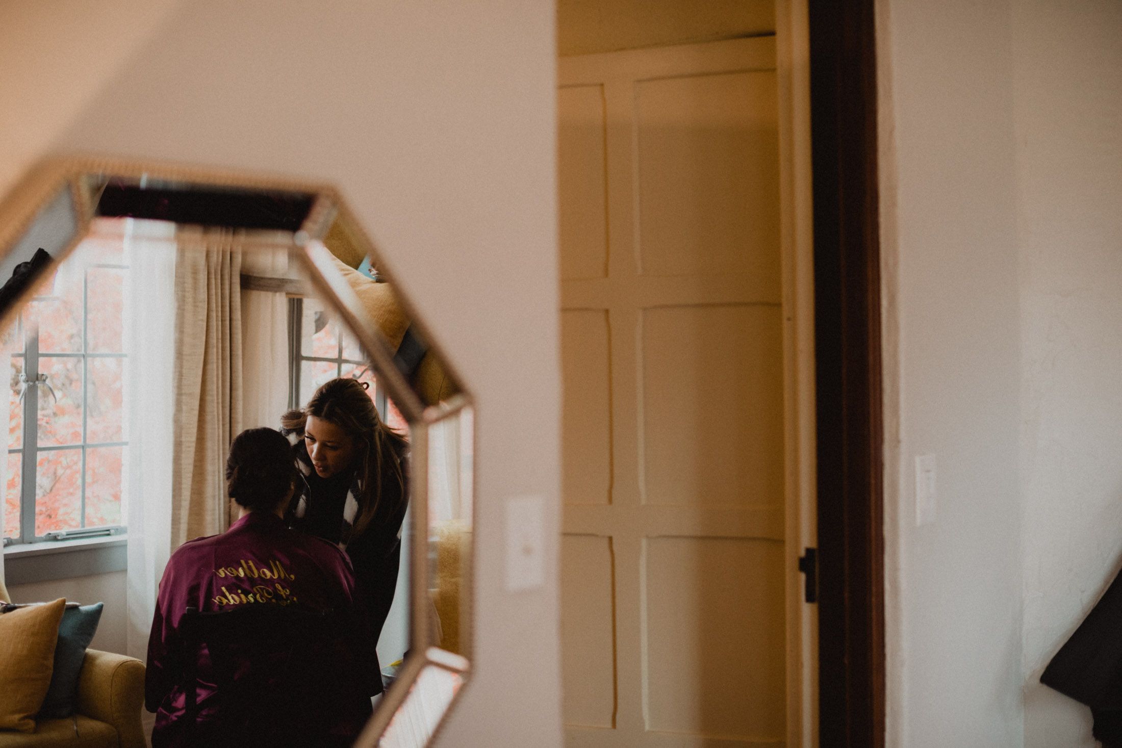 Wedding preparations in a bright sunlit room as a bride gets ready in a white robe.
