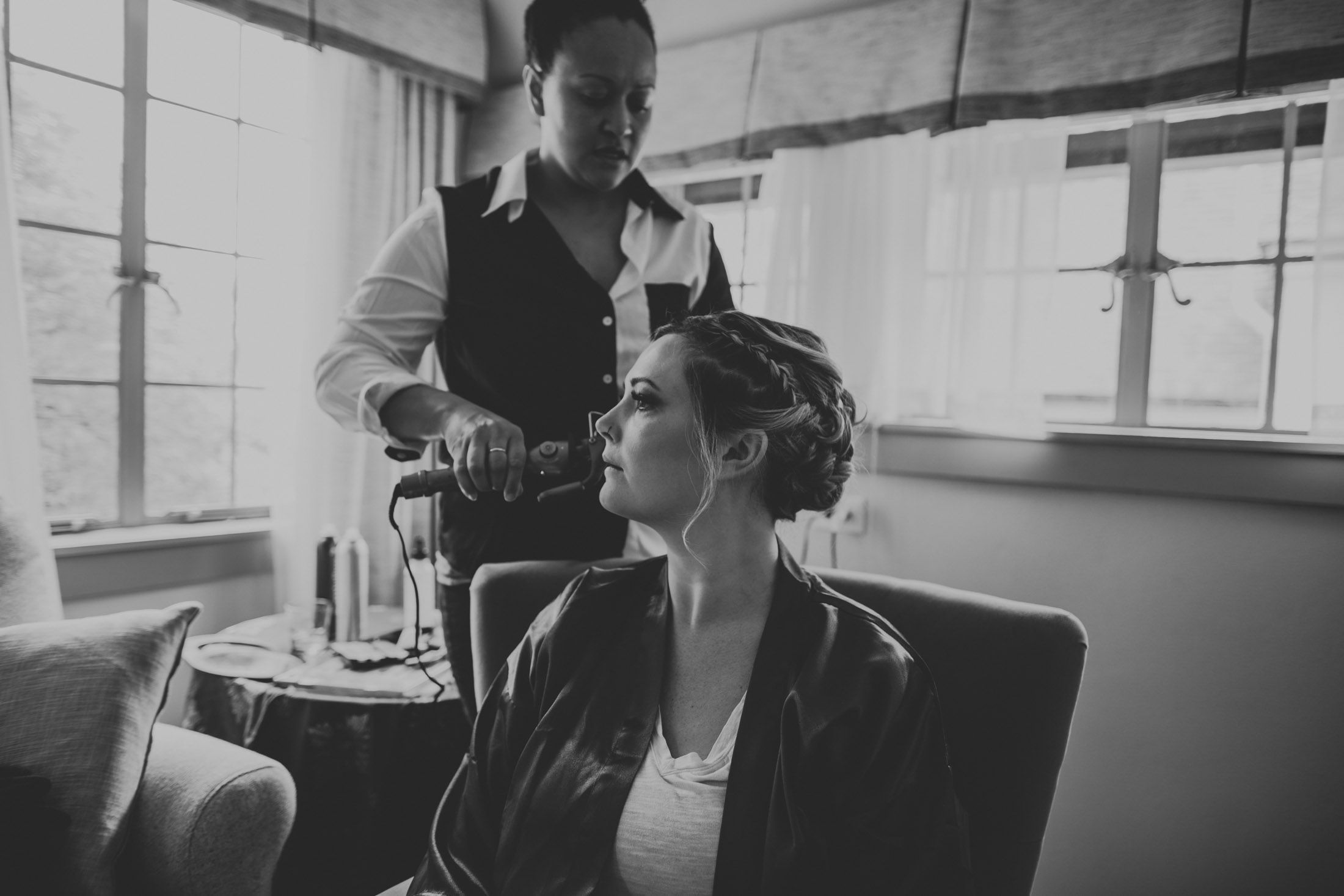 Black and white photo of people sitting together in a cozy indoor setting with natural window light.