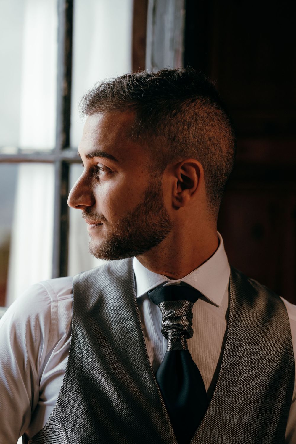 Three profile views show a well-dressed person in a vest and tie gazing thoughtfully out a window.