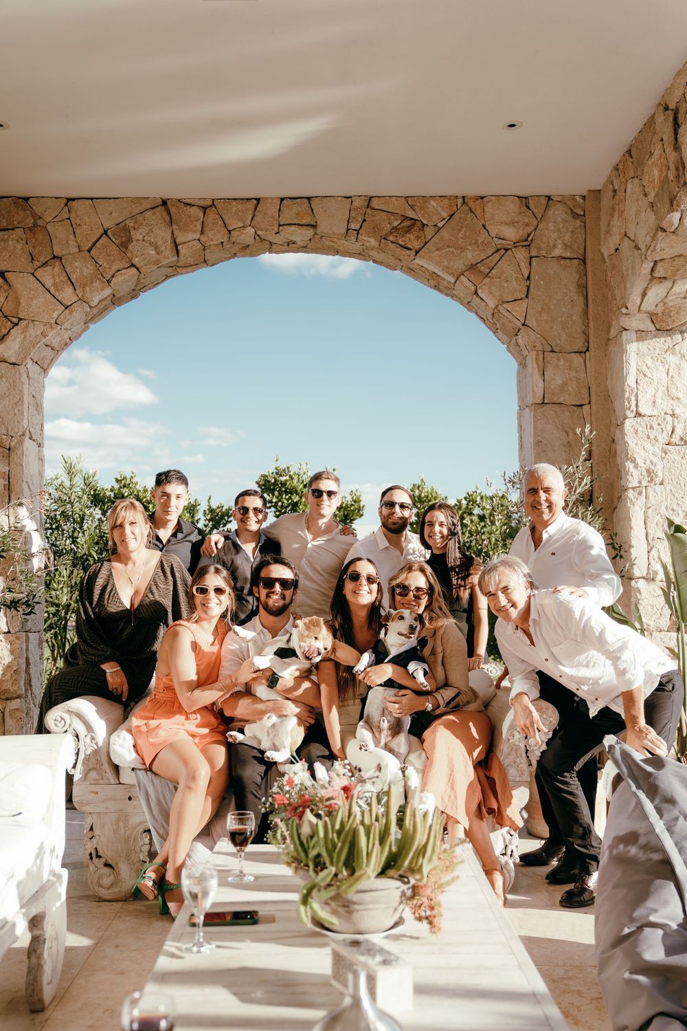 Wedding guests gathered in a stone archway terrace overlooking a scenic landscape.