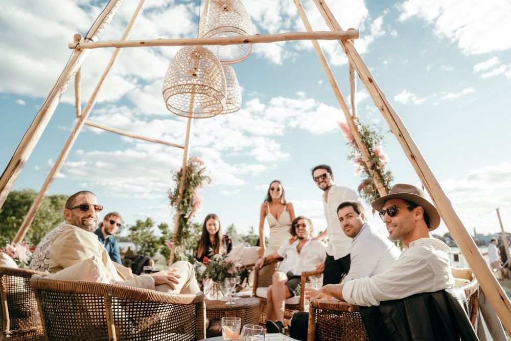 People celebrating under a bohemian teepee tent structure at an outdoor event.
