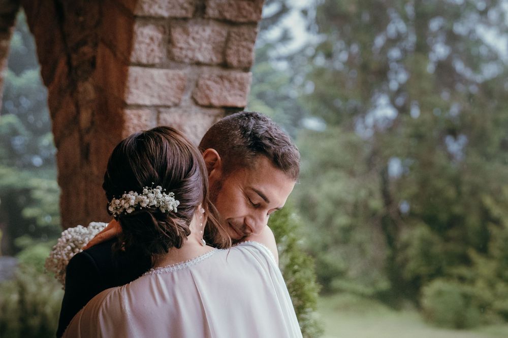 A romantic wedding ceremony moment under a rustic wooden arch with evergreen trees in the background.
