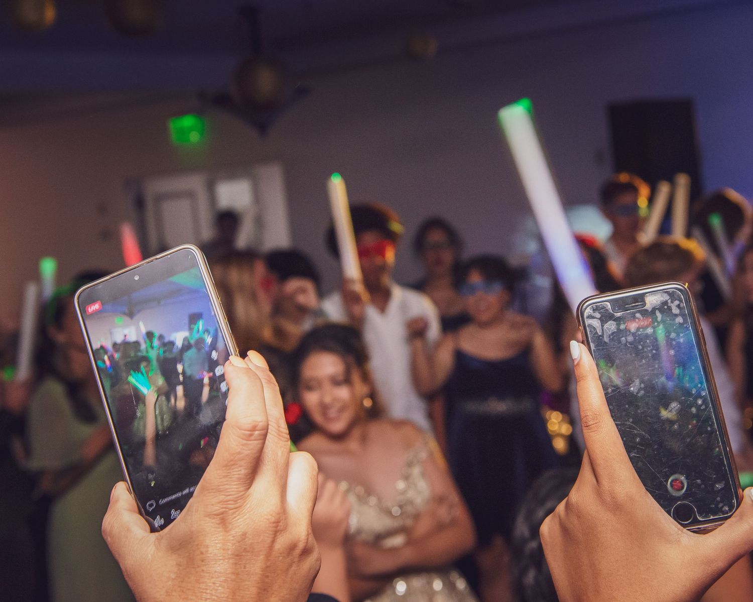 A series of hands holding glowing LED cups at a nightclub or party event.