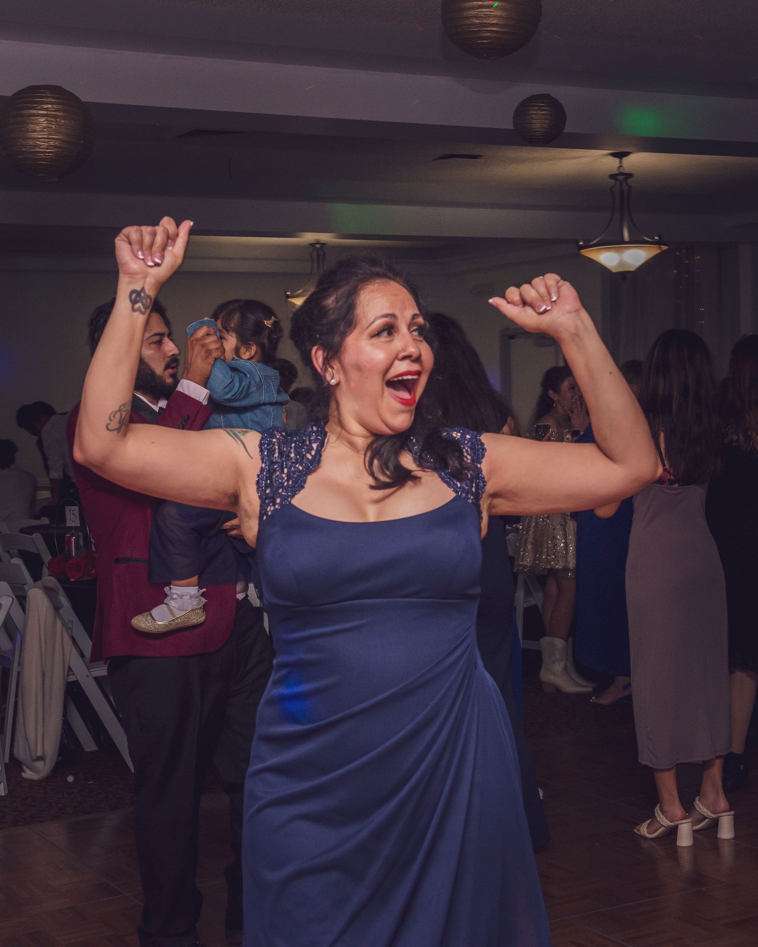 People dancing enthusiastically at an indoor celebration event with mood lighting.