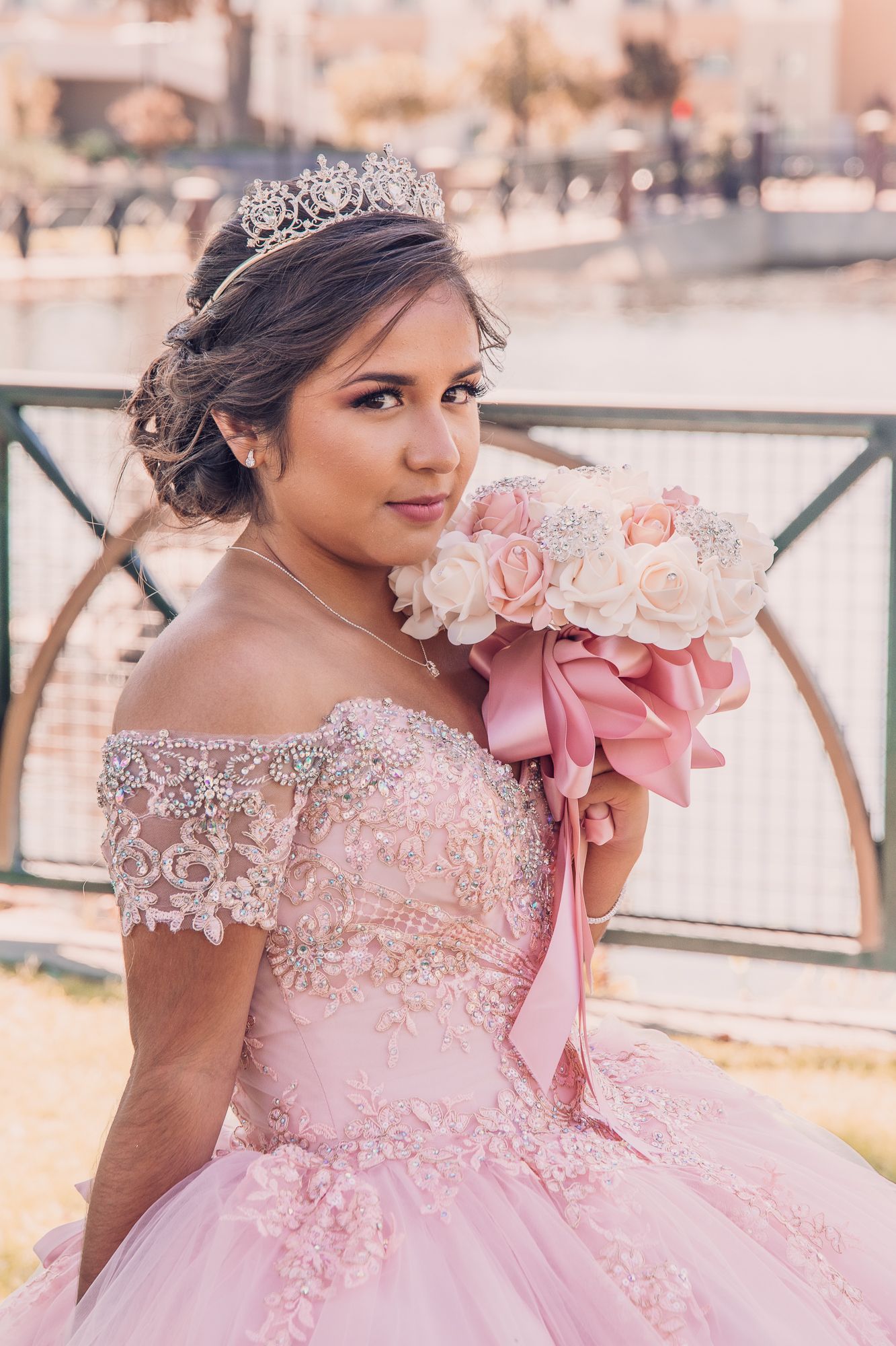 Close-up details of a pink quinceañera dress with lace, beading and a large bow accent.