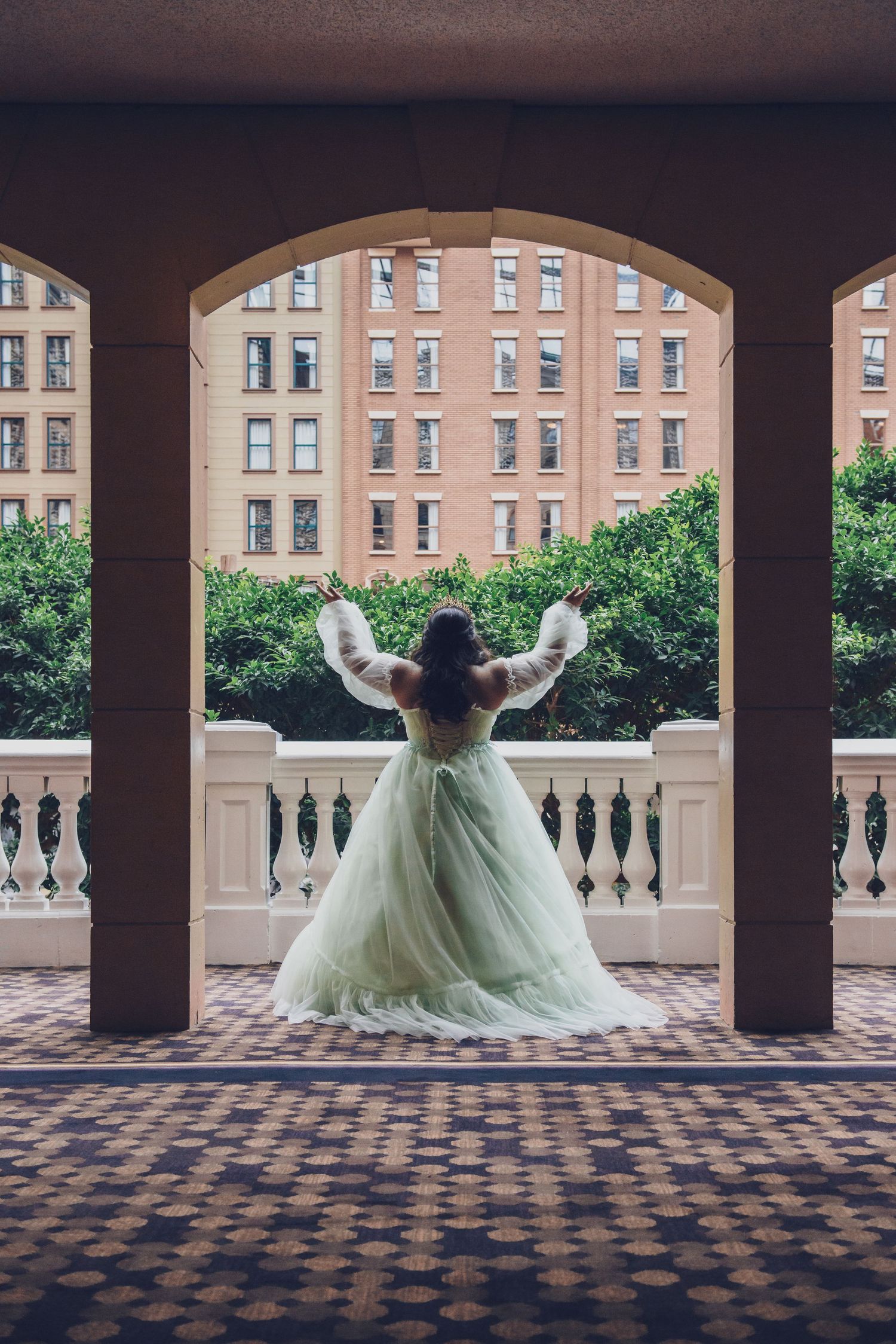 A sequence of photos showing a person in a mint green gown twirling in an arched colonnade with brick buildings in background.