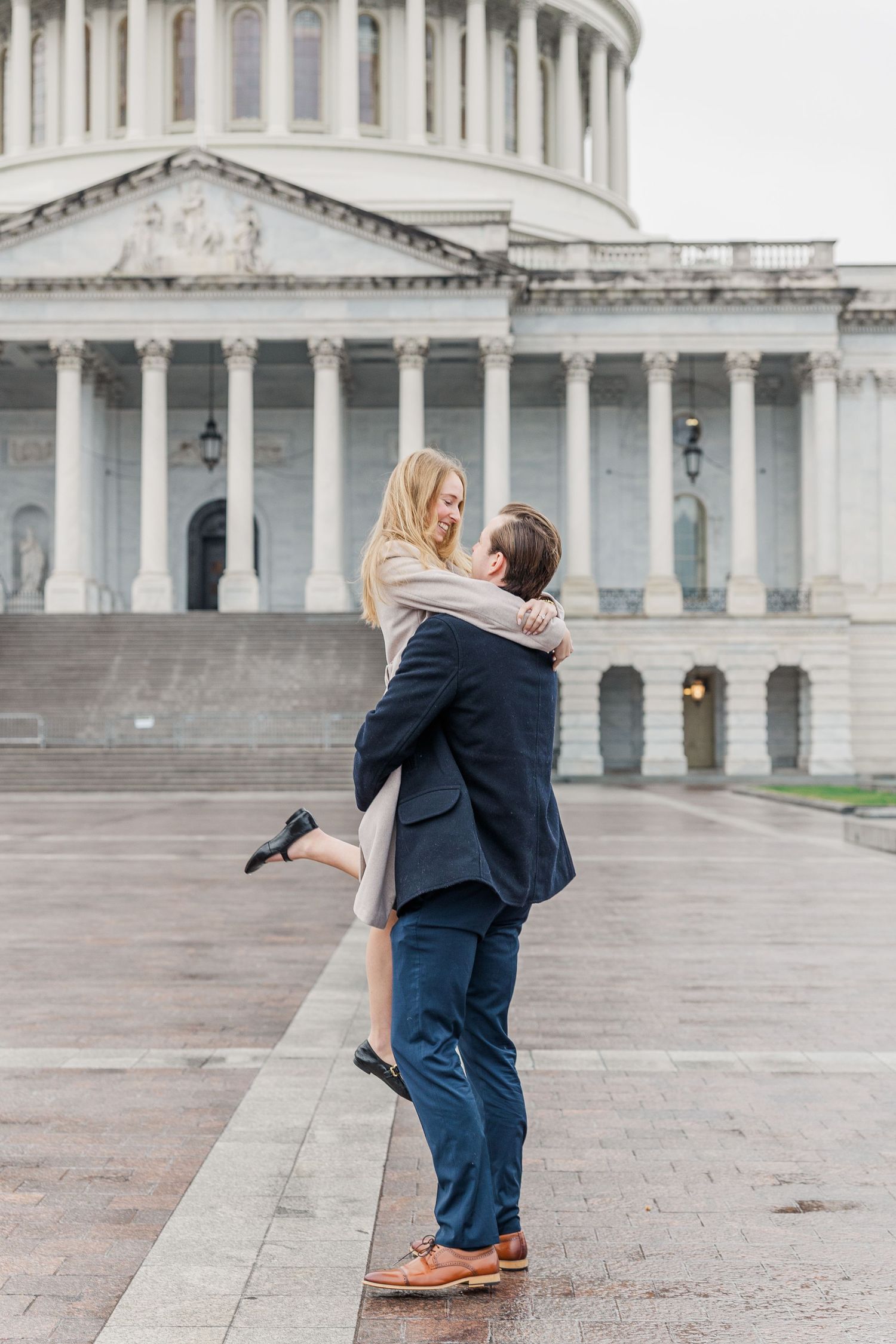 A couple embraces and spins in front of the United States Capitol Building in Washington DC during a romantic moment.