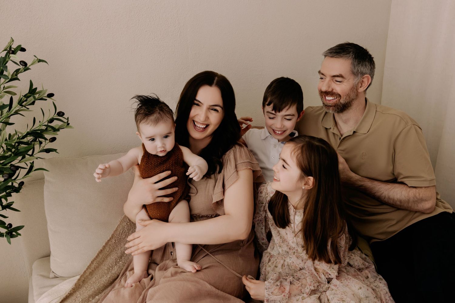 Mam, Dad, daughter and two sons sitting on sofa laughing