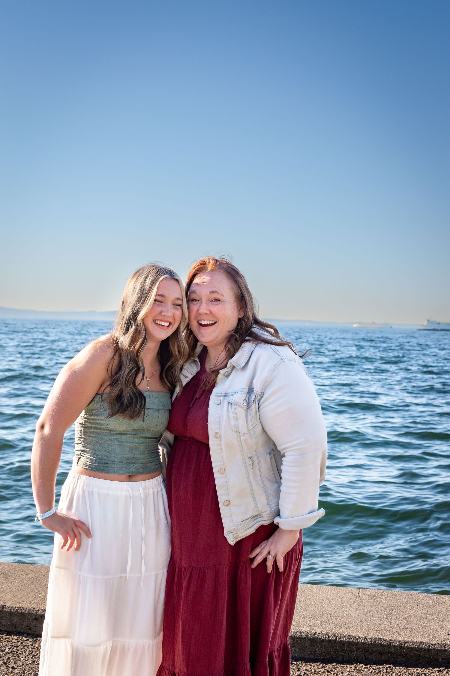 Senior graduate posing with parents during graduation photos at Alki Beach in Seattle