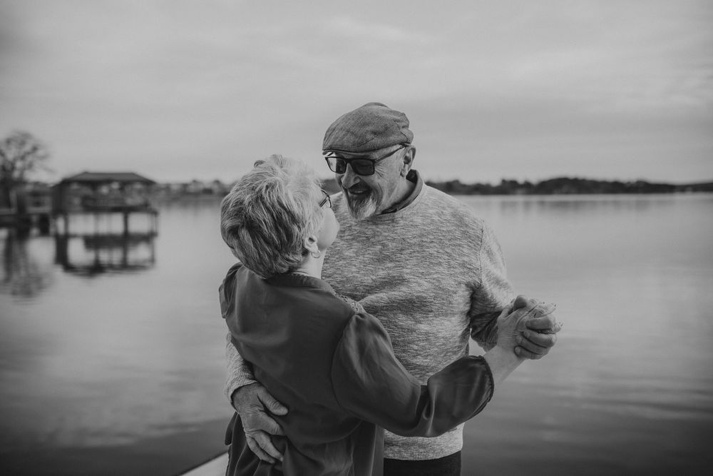 A series of black and white photos showing people embracing by a lake at sunset creating a nostalgic mood.