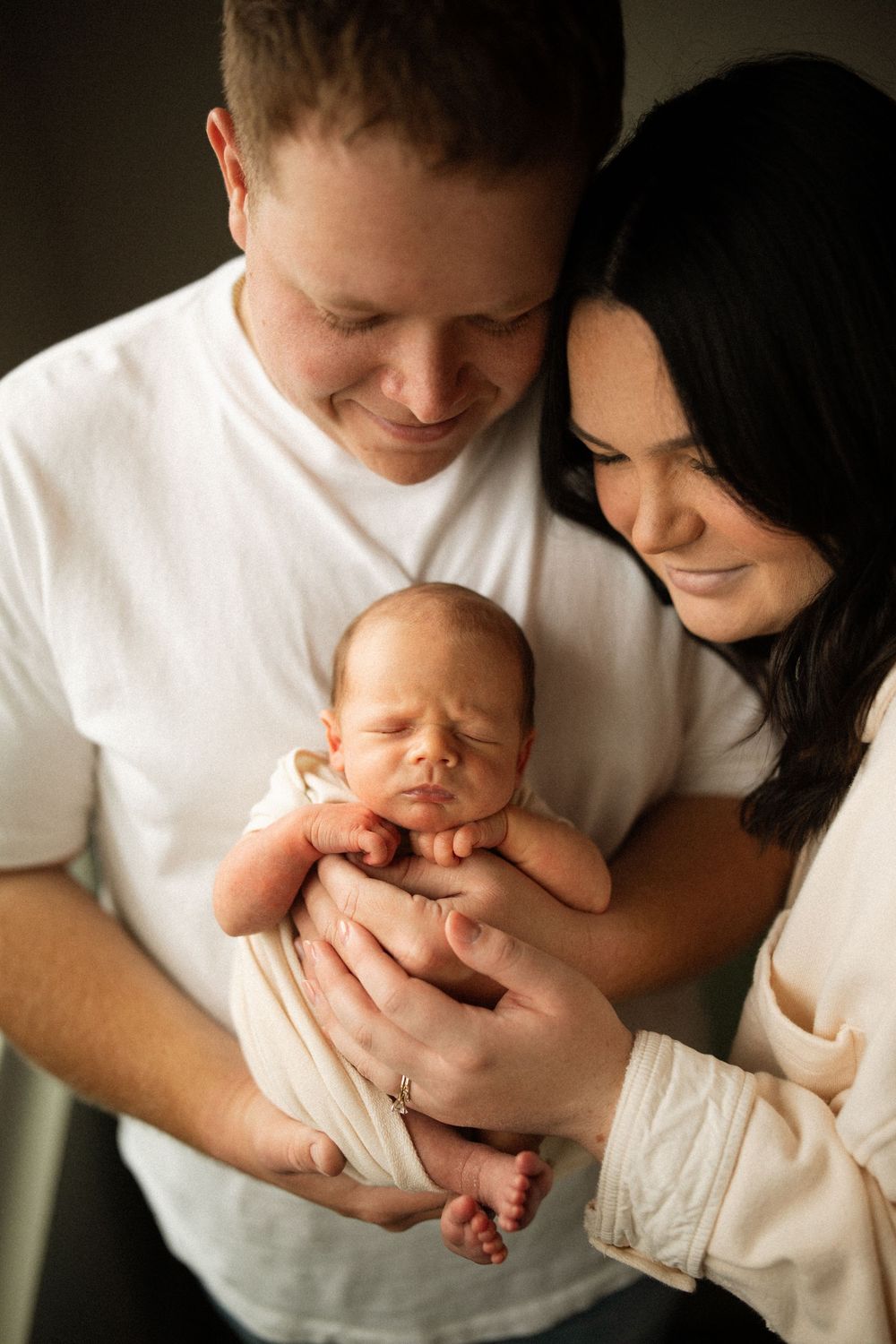A series of intimate close-up shots showing tender moments with a newborn baby being cradled.