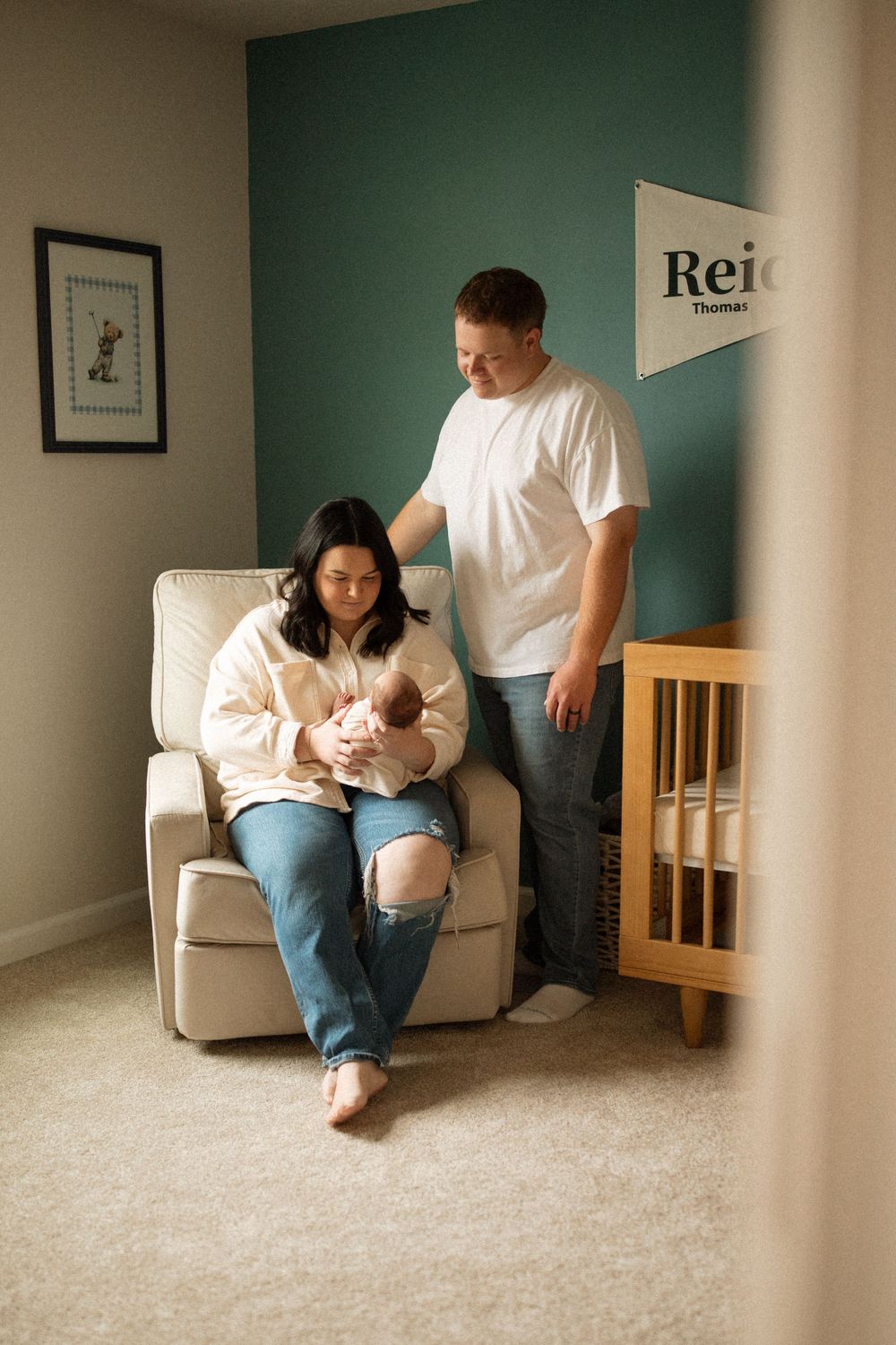 A family sitting together in a room with teal walls and carpeted floor sharing quiet moments.
