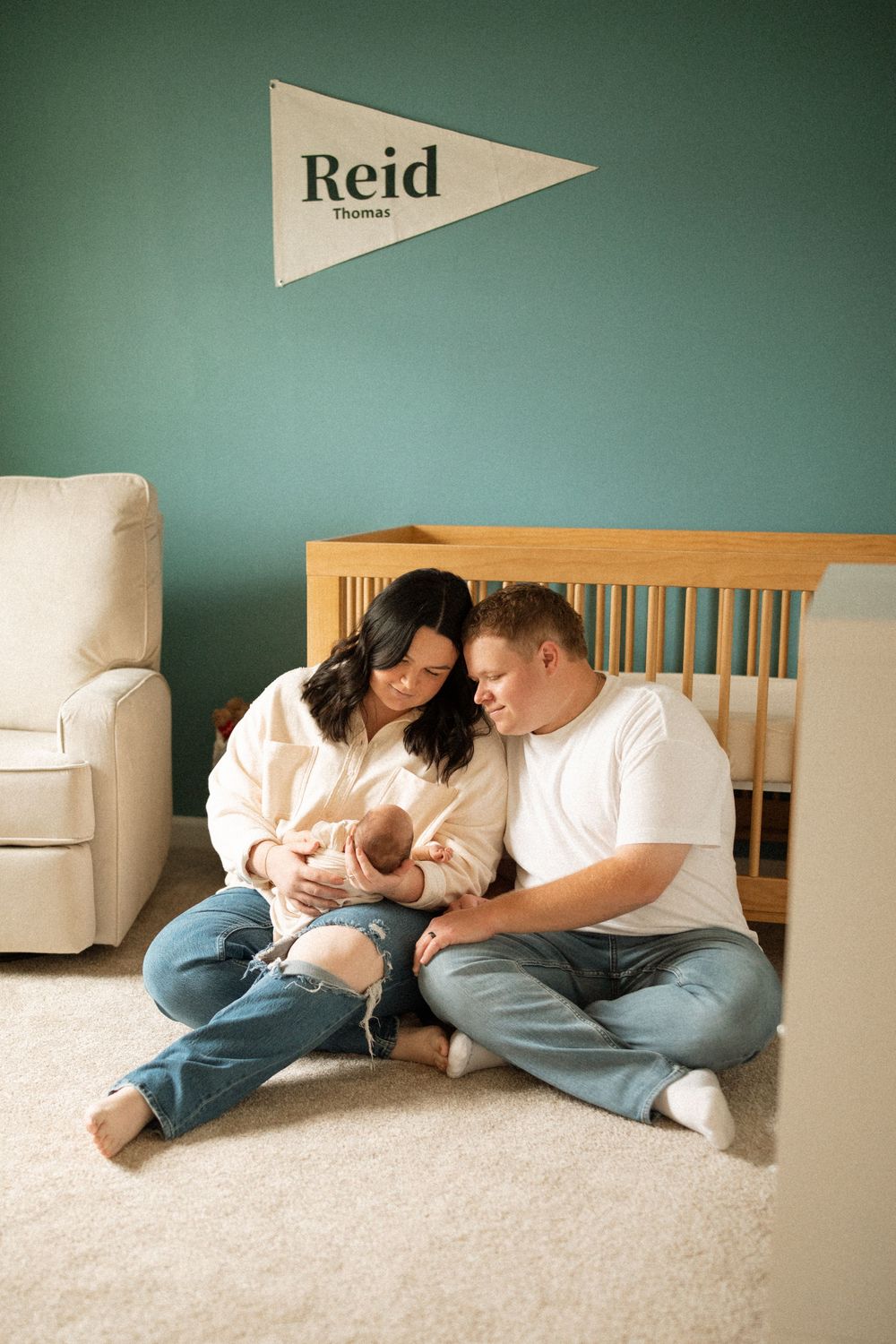 Family lying together on a carpeted floor against a teal wall with decorative pennants.
