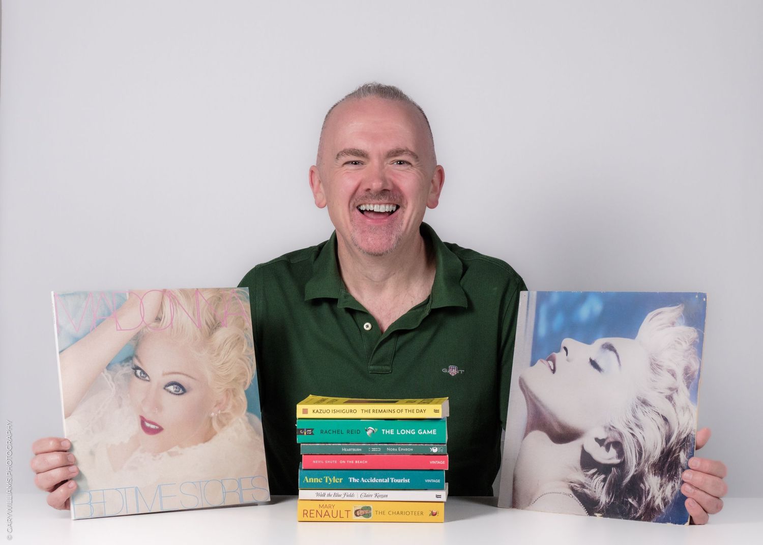 A series of photos showing someone displaying different artwork and books against a light background.