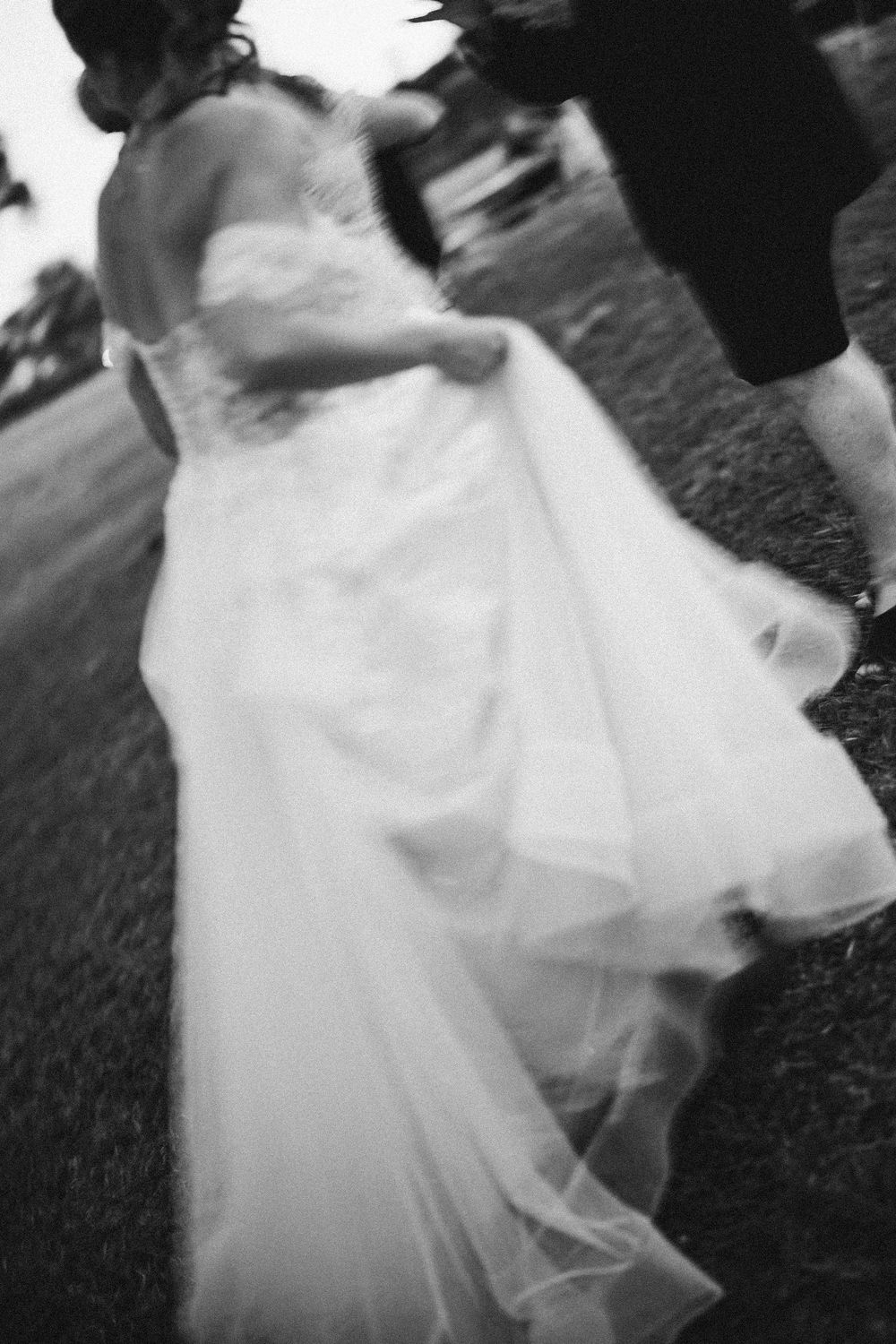 Motion blur capture of flowing white wedding dress twirling in outdoor setting.