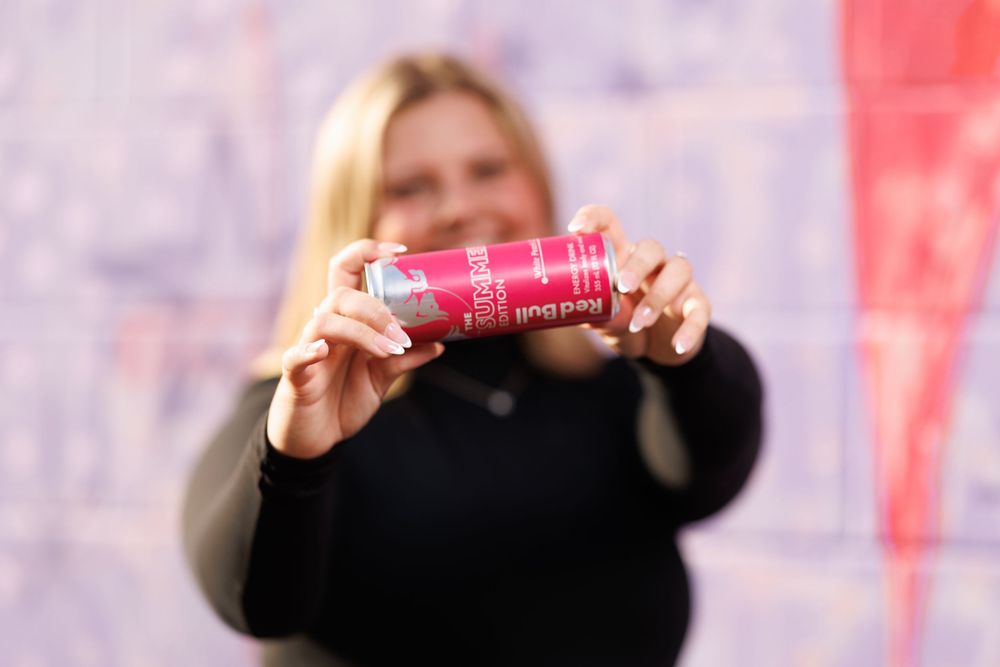 Person holding and displaying a red product against blurred background.