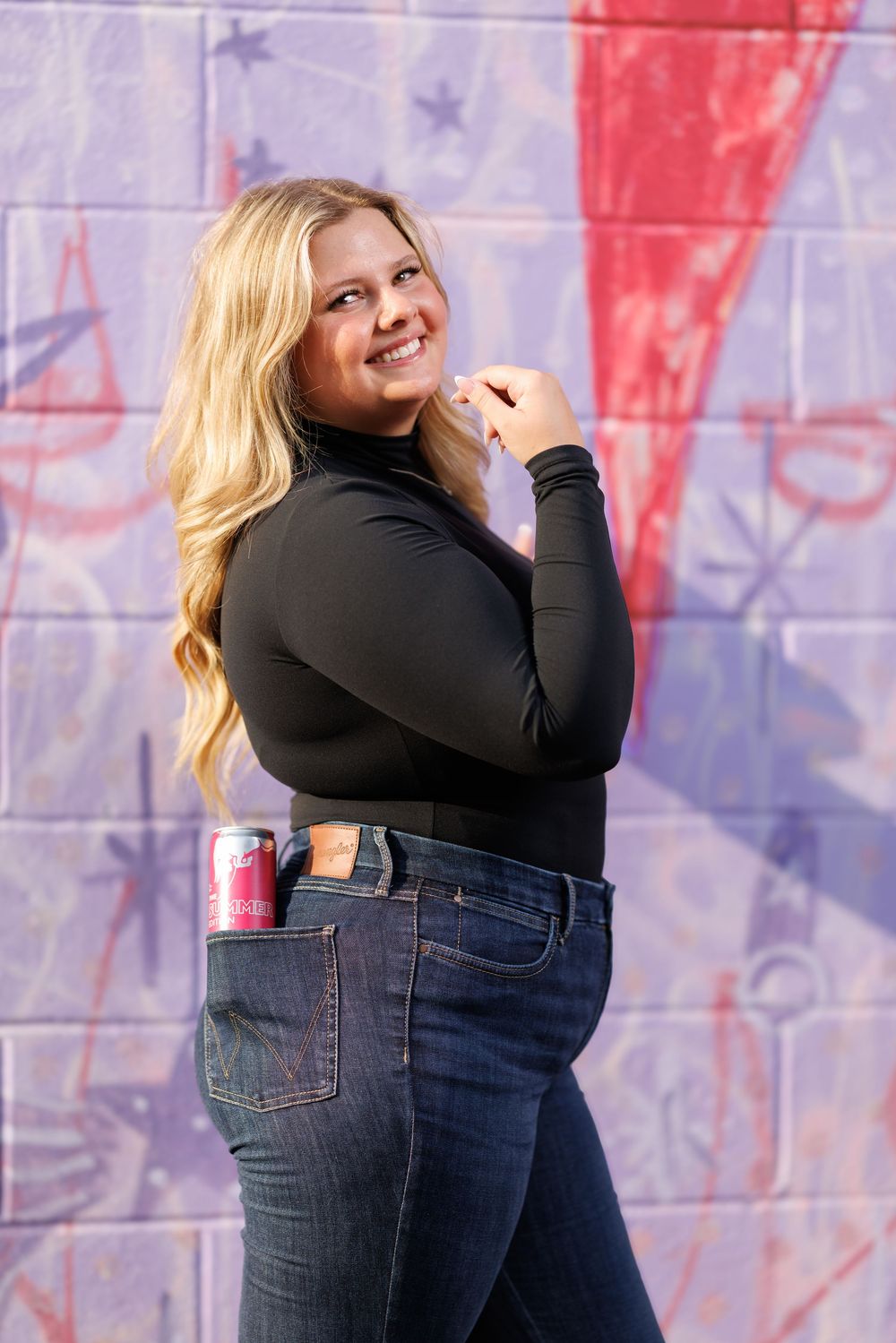 Woman in black top poses playfully against patriotic red white and blue background.