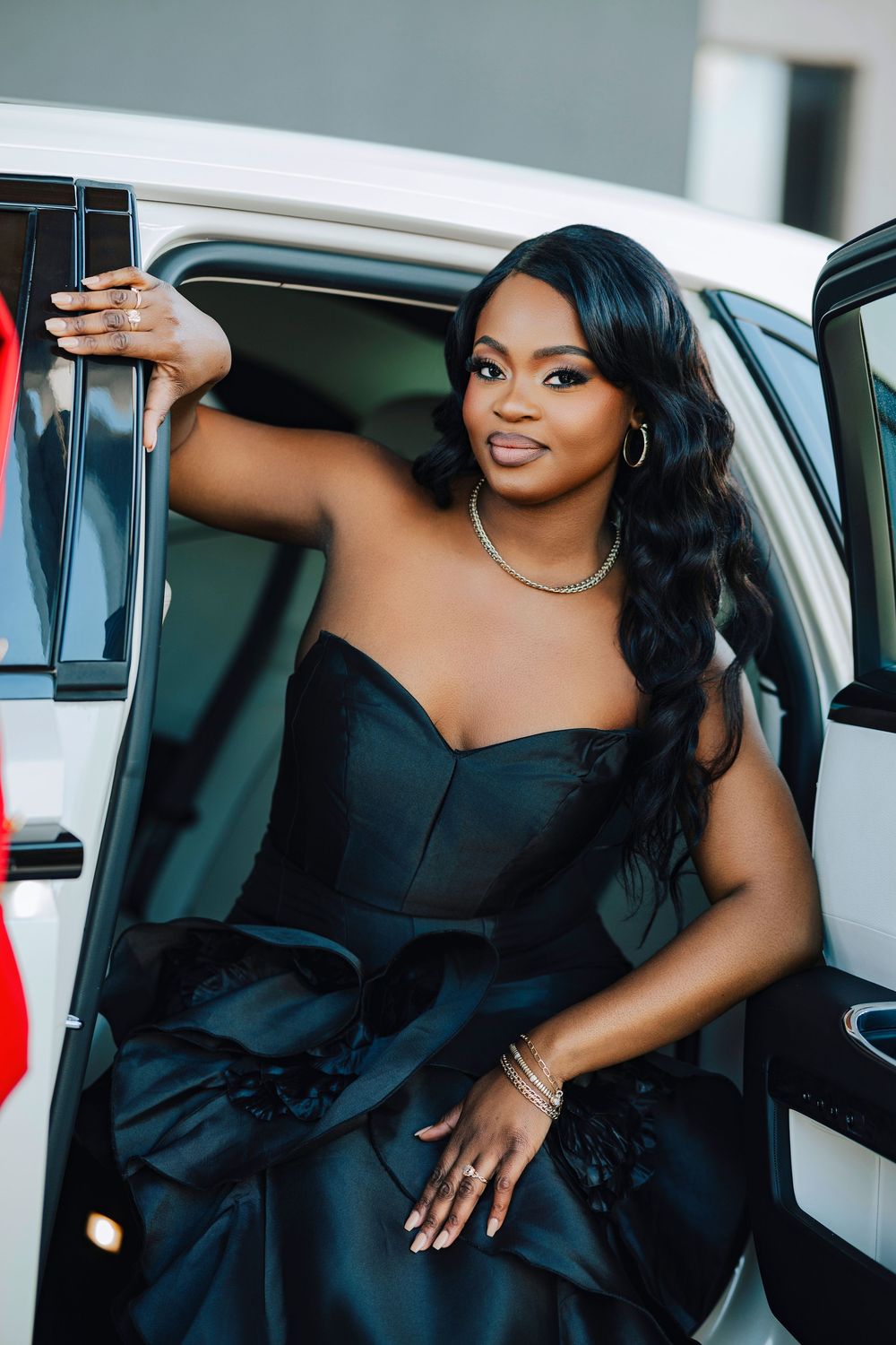 Woman in elegant black dress poses gracefully in and around a luxury car in a photo series.